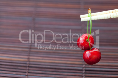 cherry and chopsticks on bamboo mat