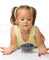 Cute little girl is eating blueberry