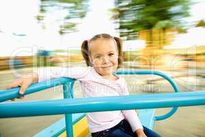 Cute little girl is riding on merry-go-round