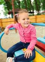 Cute little girl is riding on merry-go-round