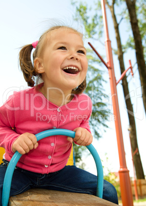 Cute little girl is swinging on see-saw