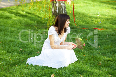 bride with a bouquet sitting on the grass