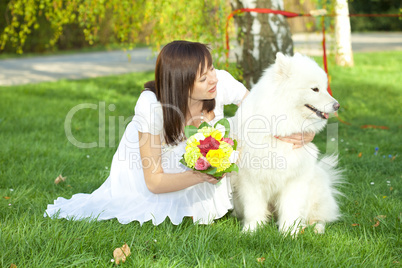 Bride with dog Samoyed sitting on the grass