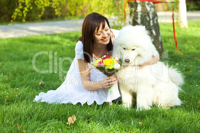 Bride with dog Samoyed sitting on the grass