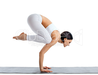 Young woman in white doing yoga pose arm balance