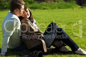 young couple sitting on the green grass