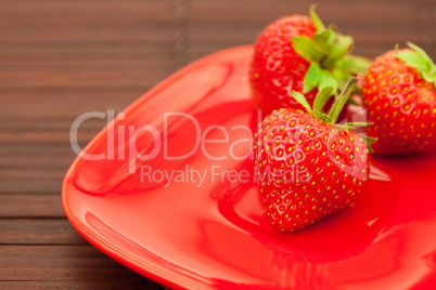 Strawberries and a plate on a bamboo mat