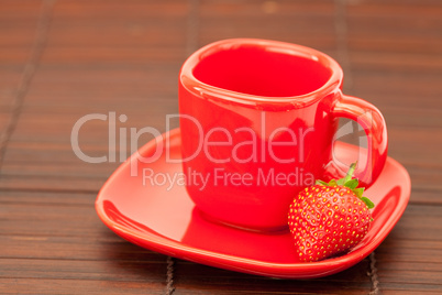 Cup and saucer and strawberries on a bamboo mat