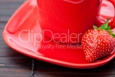 Cup and saucer and strawberries on a bamboo mat