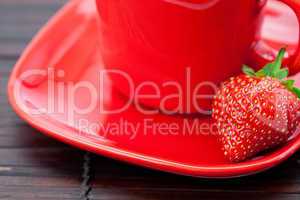 Cup and saucer and strawberries on a bamboo mat