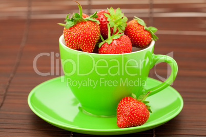 Cup and saucer and strawberries on a bamboo mat