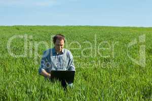 young man using laptop in the field