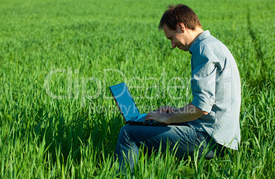 young man using laptop in the field