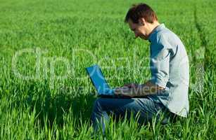 young man using laptop in the field