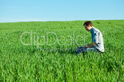 young man using laptop in the field