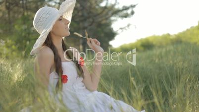 Pretty smiling young woman sitting on a swaying grass