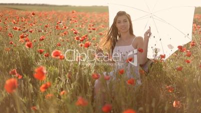 Young woman with white umbrella sitting on chair among poppies