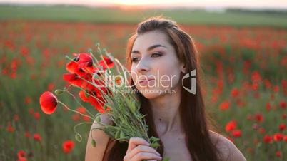 Young woman with bouquet of red poppies on meadow