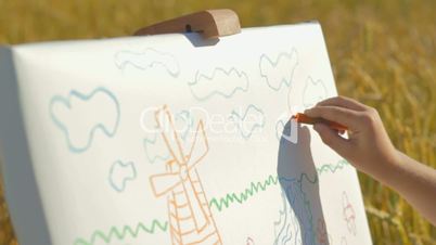 Woman helping little boy  in drawing on the wheat field