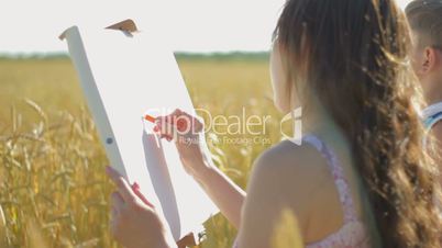 Young woman with boy drawing with crayons in the field