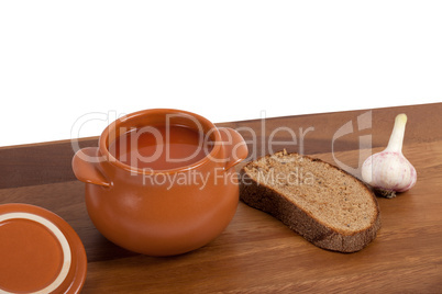 Soup in clay pot on wooden table