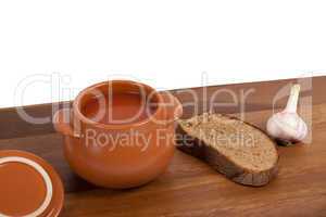 Soup in clay pot on wooden table