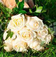 bridal bouquet to the bride's hand lying on green grass