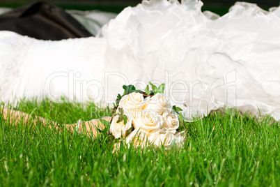 bridal bouquet in her hand the bride against the dress lying on