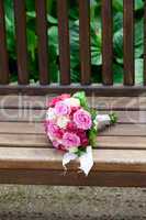 beautiful bridal bouquet lying on the wooden benches