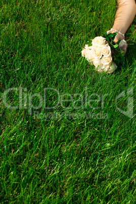 bridal bouquet to the bride's hand lying on green grass