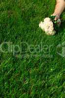 bridal bouquet to the bride's hand lying on green grass