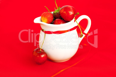 milk jug ribbon  cherry and strawberry on a red background