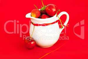 milk jug ribbon  cherry and strawberry on a red background