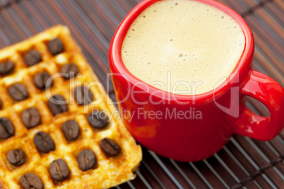 cup of cappuccino wafers and coffee beans on a bamboo mat