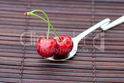 cherry in spoon on a bamboo mat cherry in spoon on a bamboo mat