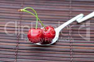 cherry in spoon on a bamboo mat