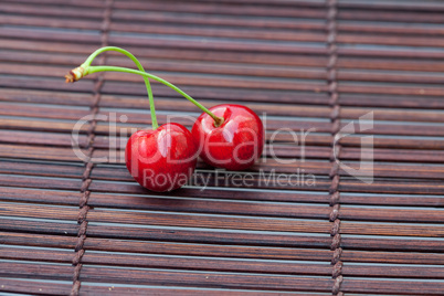two cherries on a bamboo mat