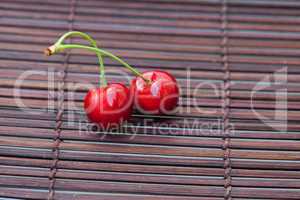 two cherries on a bamboo mat