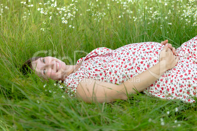 Pregnant woman lie in chamomile