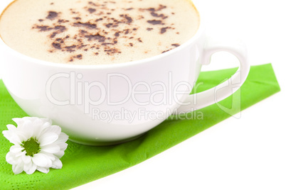 cup of cappuccino and a white flower on a green cloth