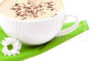 cup of cappuccino and a white flower on a green cloth