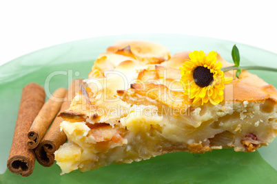 piece of apple pie on a plate and a flower isolated on white