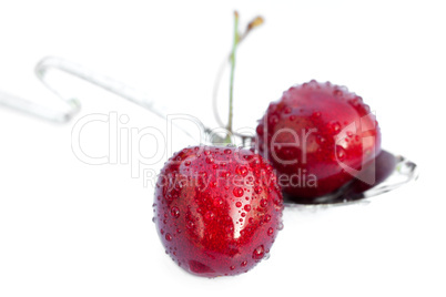 cherries with drops of water in the spoon isolated on white