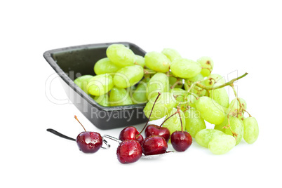 cherries with drops of water in a spoon and a bowl of grapes iso