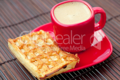 cup of cappuccino and waffles on a bamboo mat