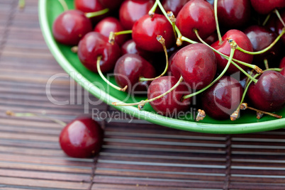 plate of cherries on a bamboo mat