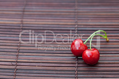 two cherries on a bamboo mat