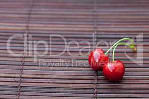 two cherries on a bamboo mat