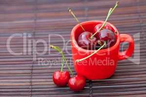 cherry and red cup on a bamboo mat