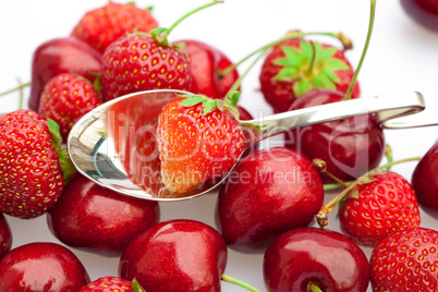 cherry and strawberry in a spoon isolated on white